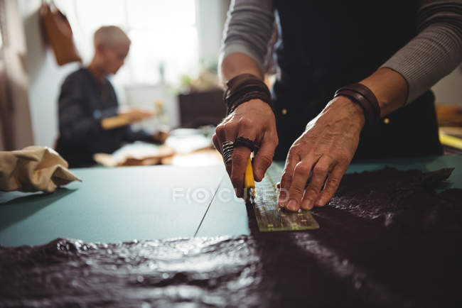 Mid-section of craftswoman cutting leather in workshop — Stock Photo