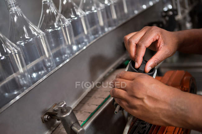 Cropped hands of employee operating machine in juice factory — Stock Photo