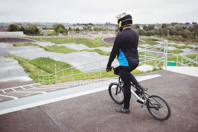 Ciclista de pie con bicicleta BMX en la rampa de salida en skatepark - foto de stock
