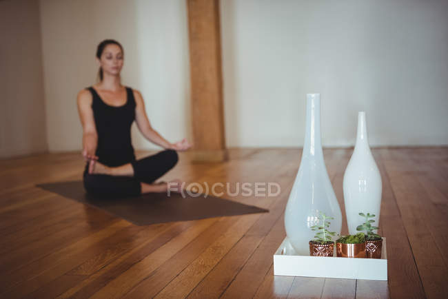 Vasi di vetro con piante in vaso sul pavimento in legno con donna che pratica yoga in studio — Foto stock