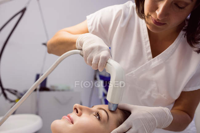 Médico dando tratamiento cosmético a paciente femenina en clínica estética - foto de stock
