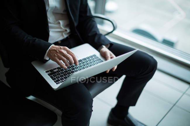 Geschäftsmann benutzt Laptop im Wartebereich am Flughafen-Terminal — Stockfoto