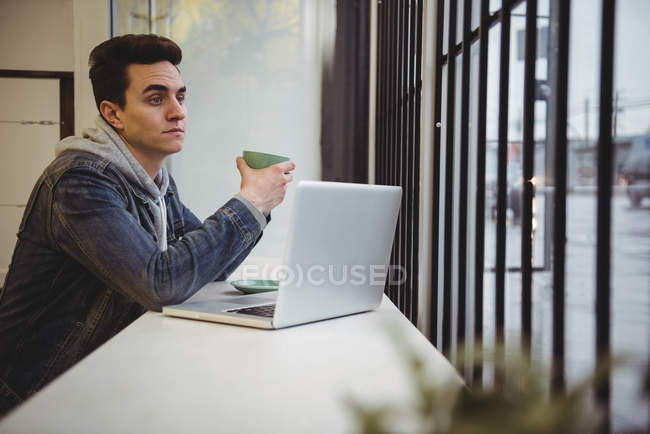 Задуманный человек держит чашку кофе в кофейне — стоковое фото