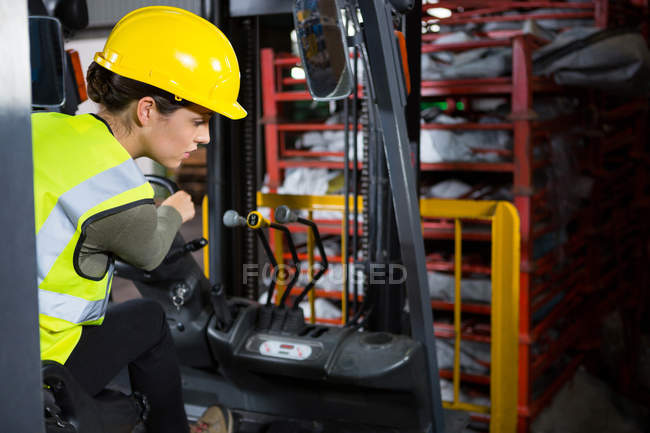 Schöne Arbeiterin fährt Gabelstapler in Lagerhalle — Stockfoto