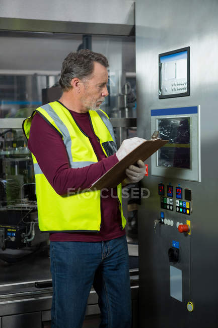 Trabalhador manual analisando máquinas na fábrica — Fotografia de Stock
