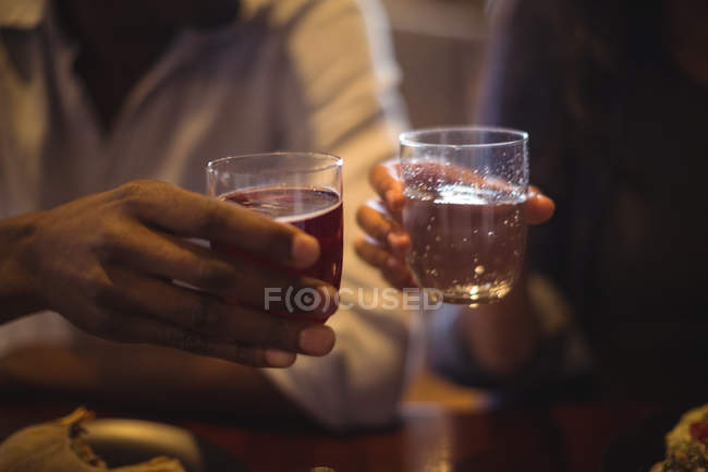 Primo piano di coppia che brinda a bicchieri di bevanda in ristorante — Foto stock