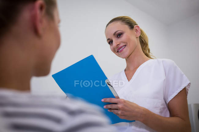 Усміхаючись лікар тримає медичного висновку за пацієнта клініки — стокове фото