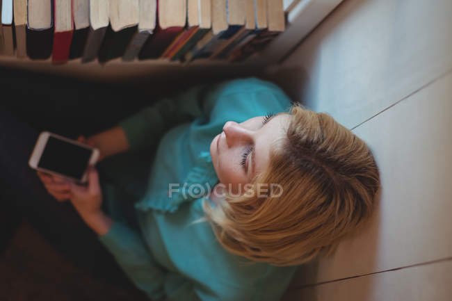 Thoughtful woman holding mobile phone at home — Stock Photo