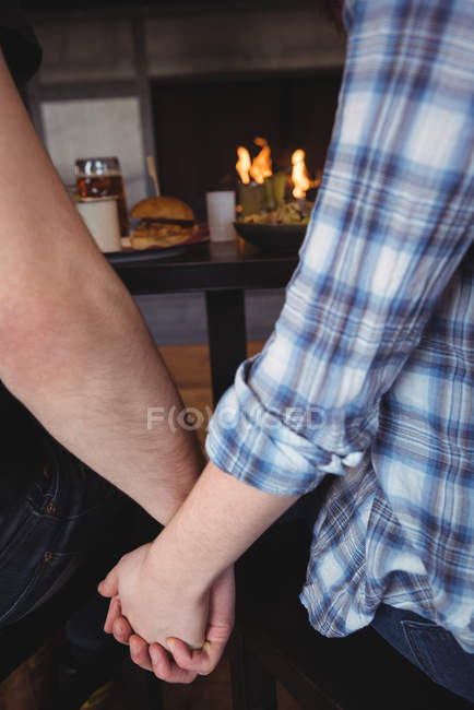 Close-up of couple sitting at bar counter holding hands — Stock Photo