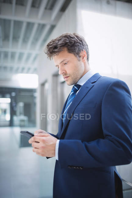 Hombre de negocios usando el teléfono móvil en la oficina - foto de stock