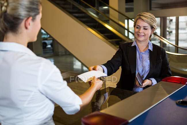 Empresaria mostrando tarjeta de embarque en el mostrador de facturación en el aeropuerto — Stock Photo