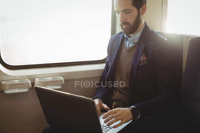 Homme d'affaires utilisant un ordinateur portable pendant un voyage en train — Photo de stock