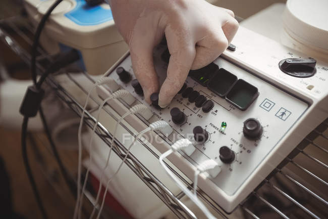 Primo piano del dispositivo di elettrostimolazione di regolazione della mano maschile in clinica — Foto stock