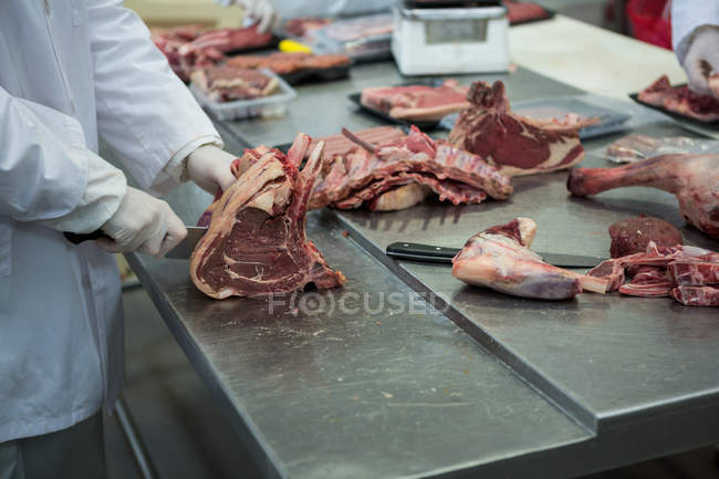 Крупный план мясников, режущих мясо на мясокомбинате — стоковое фото