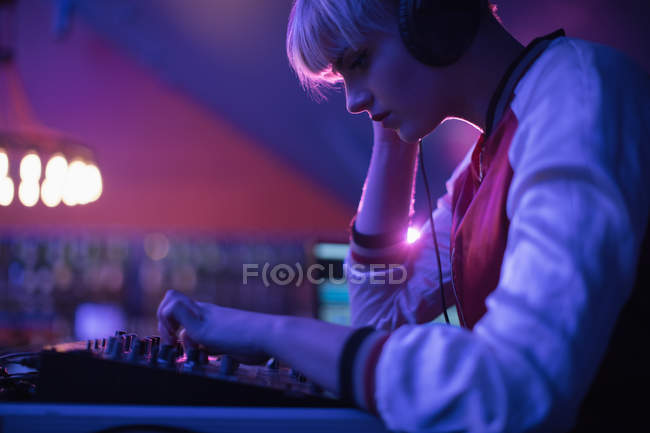 Feminino dj ouvir fones de ouvido enquanto toca música no bar — Fotografia de Stock