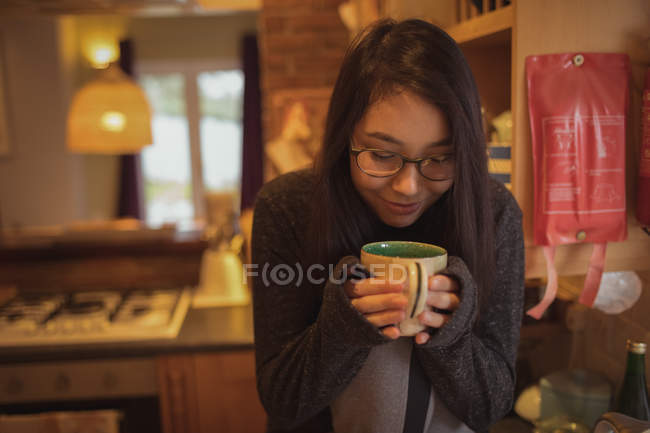 Mujer tomando café en la cocina en casa - foto de stock