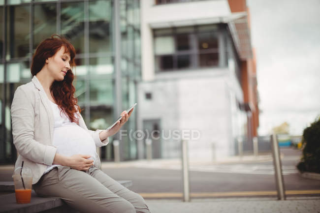 Pregnant businesswoman holding digital tablet in office premises — Stock Photo