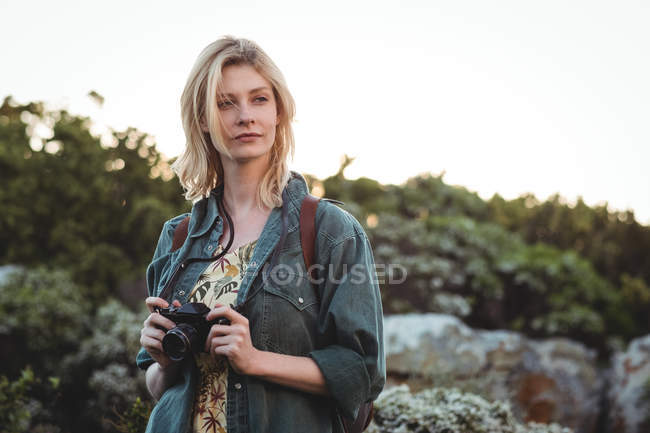 Thoughtful woman holding digital camera — Stock Photo