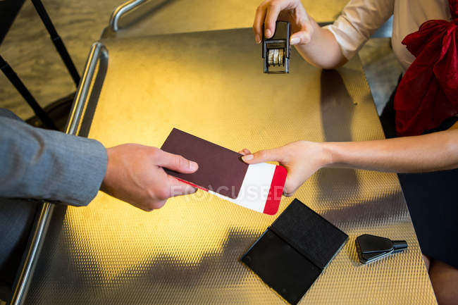 Hands of airline check-in attendant handing passport to passenger at airport check-in counter — Stock Photo