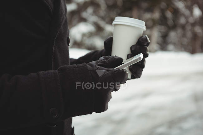 Mid section of man in warm clothing using mobile phone during winter — Stock Photo