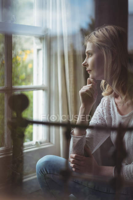 Schöne Frau schaut durch Fenster im Schlafzimmer zu Hause — Stockfoto