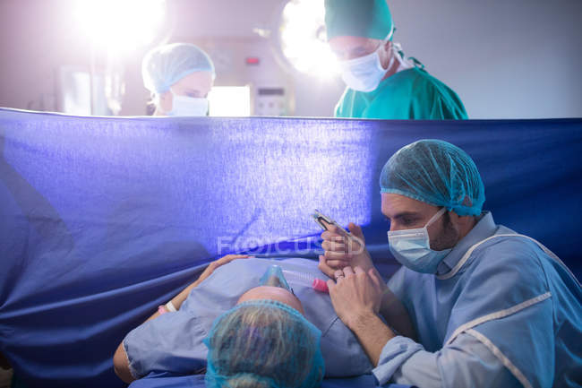 Médecin examinant la femme enceinte pendant l'accouchement en salle d'opération — Photo de stock