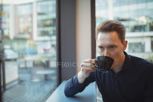 Ejecutivo masculino tomando café en el mostrador en la cafetería - foto de stock