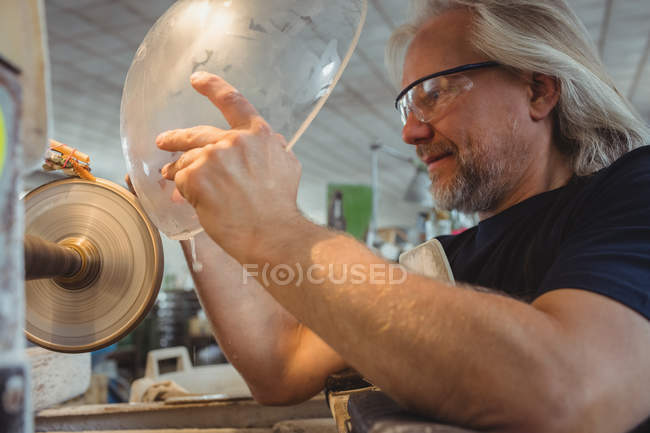 Soplador de vidrio pulido y molienda de una cristalería en la fábrica de soplado de vidrio - foto de stock