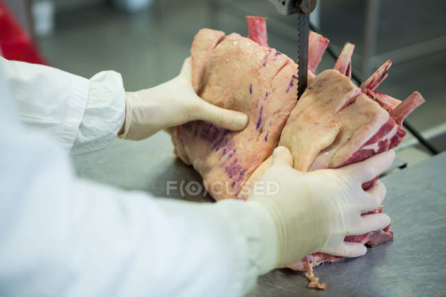 Крупный план мясника, режущего мясо с помощью машины для резки мяса — стоковое фото