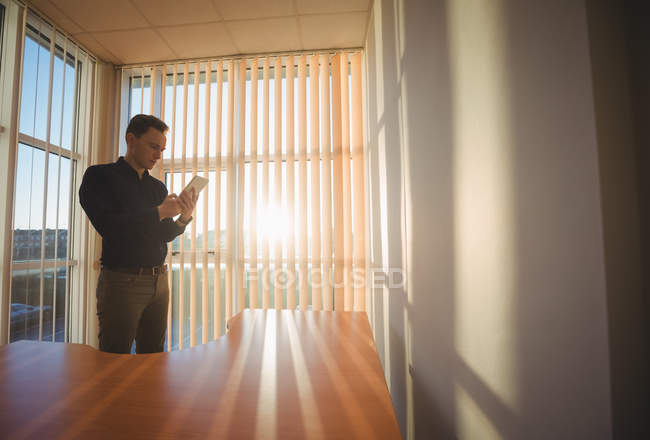 Homme exécutif utilisant tablette numérique près des stores de fenêtre dans le bureau — Photo de stock
