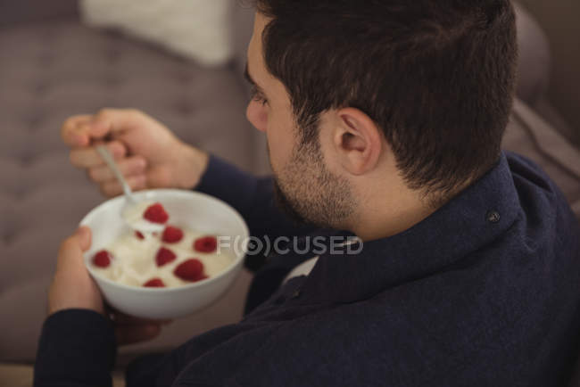 Homme prenant le petit déjeuner sur canapé à la maison — Photo de stock