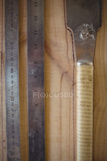 Gros plan des règles et de la scie tireuse sur fond en bois — Photo de stock