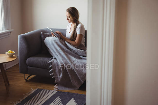 Frau nutzt digitales Tablet auf Sofa im Wohnzimmer — Stockfoto