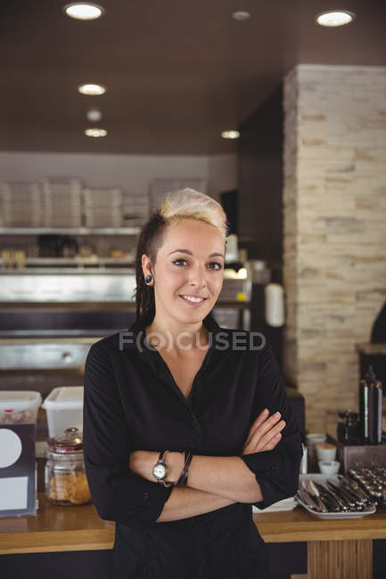 Woman standing with arms crossed in kitchen at cafe — Stock Photo