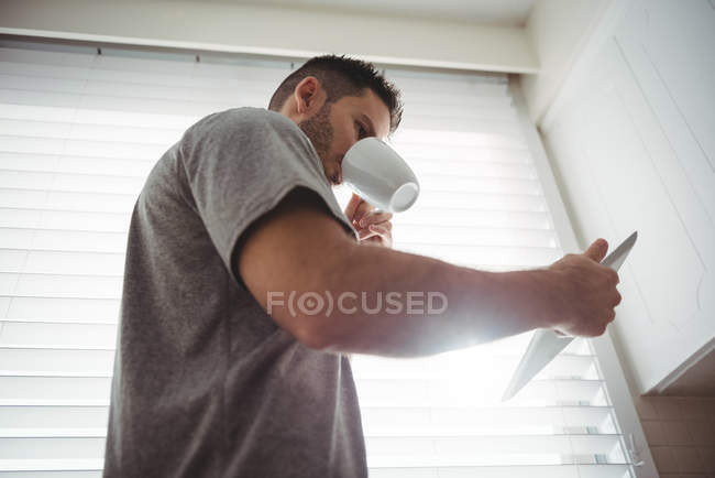 Mann benutzt digitales Tablet beim Kaffee in der heimischen Küche — Stockfoto