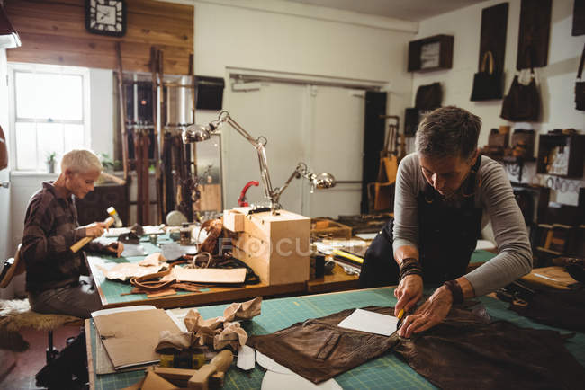 Attentive craftswoman cutting leather in workshop — Stock Photo