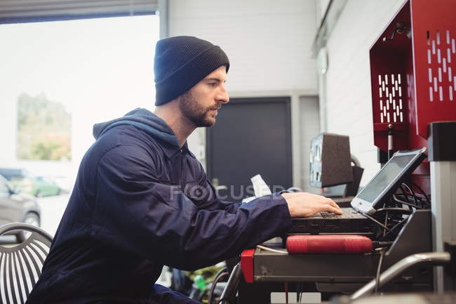 Механик с помощью ноутбука в ремонтном гараже — стоковое фото