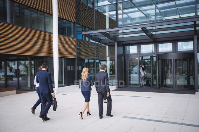 Grupo de empresarios que entran en un edificio de oficinas - foto de stock