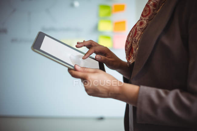 Средняя секция бизнесвумен с помощью цифрового планшета в офисе — стоковое фото