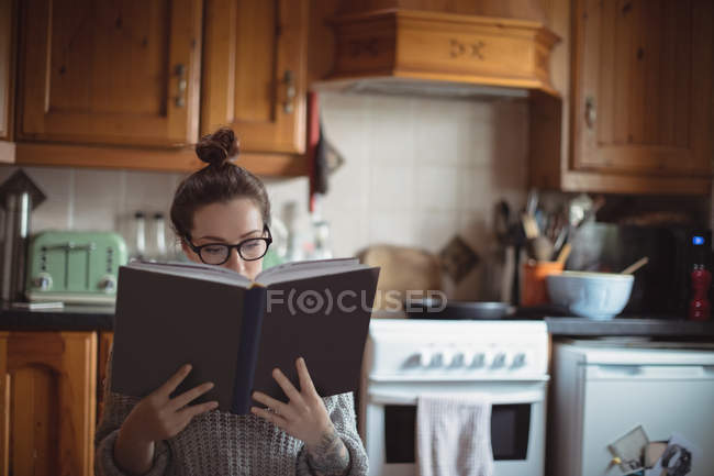 Mulher leitura livro na cozinha em casa — Fotografia de Stock