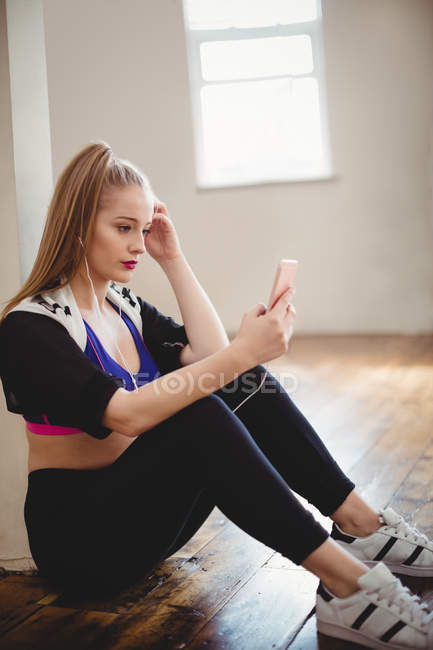 Красивая женщина слушает музыку на мобильном телефоне в студии — стоковое фото