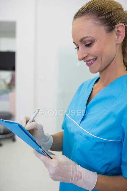 Жінка-стоматолог пише медичний звіт у клініці — стокове фото