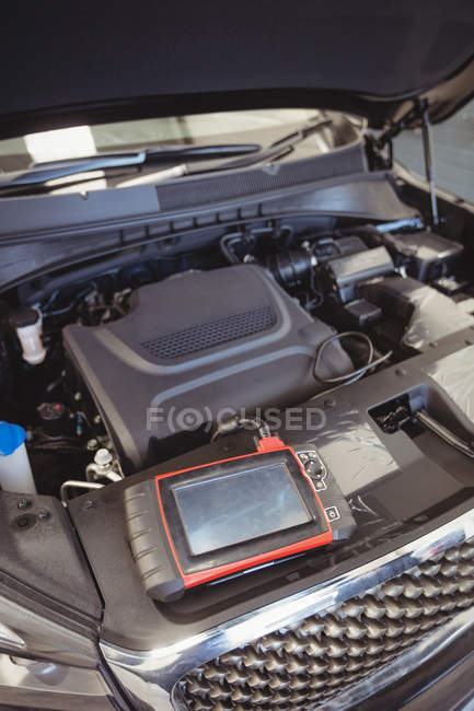 Carro com tampa aberta e dispositivo de diagnóstico na garagem de reparação — Fotografia de Stock