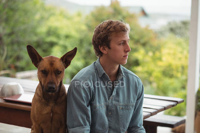 Thoughtful man sitting with his dog outside house — Stock Photo