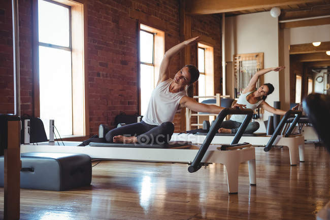 Donne che praticano pilates sui riformatori in palestra — Foto stock