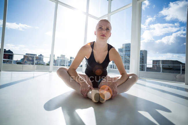 Балерина растягивается на полу в студии — стоковое фото