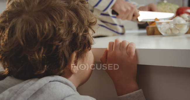 Son watching father preparing vegetables in kitchen — Stock Photo