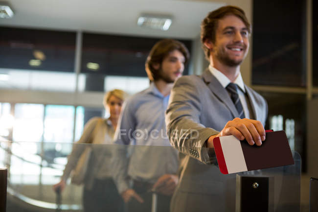 Empresário de pé com cartão de embarque no balcão de check-in no aeroporto — Fotografia de Stock
