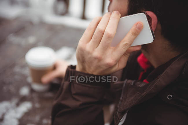 Чоловік по телефону, маючи каву на гірськолижному курорті — стокове фото