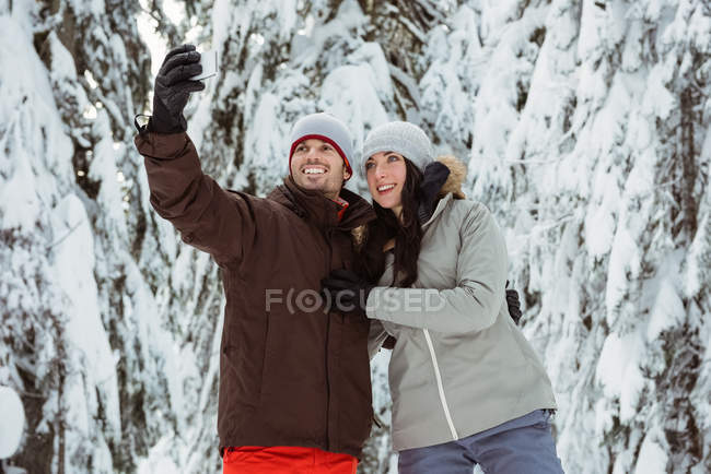 Happy skier couple taking a selfie on snow covered mountain — Stock Photo